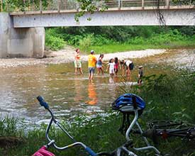 Group of children standing in a shallow river bed while working outdoors.